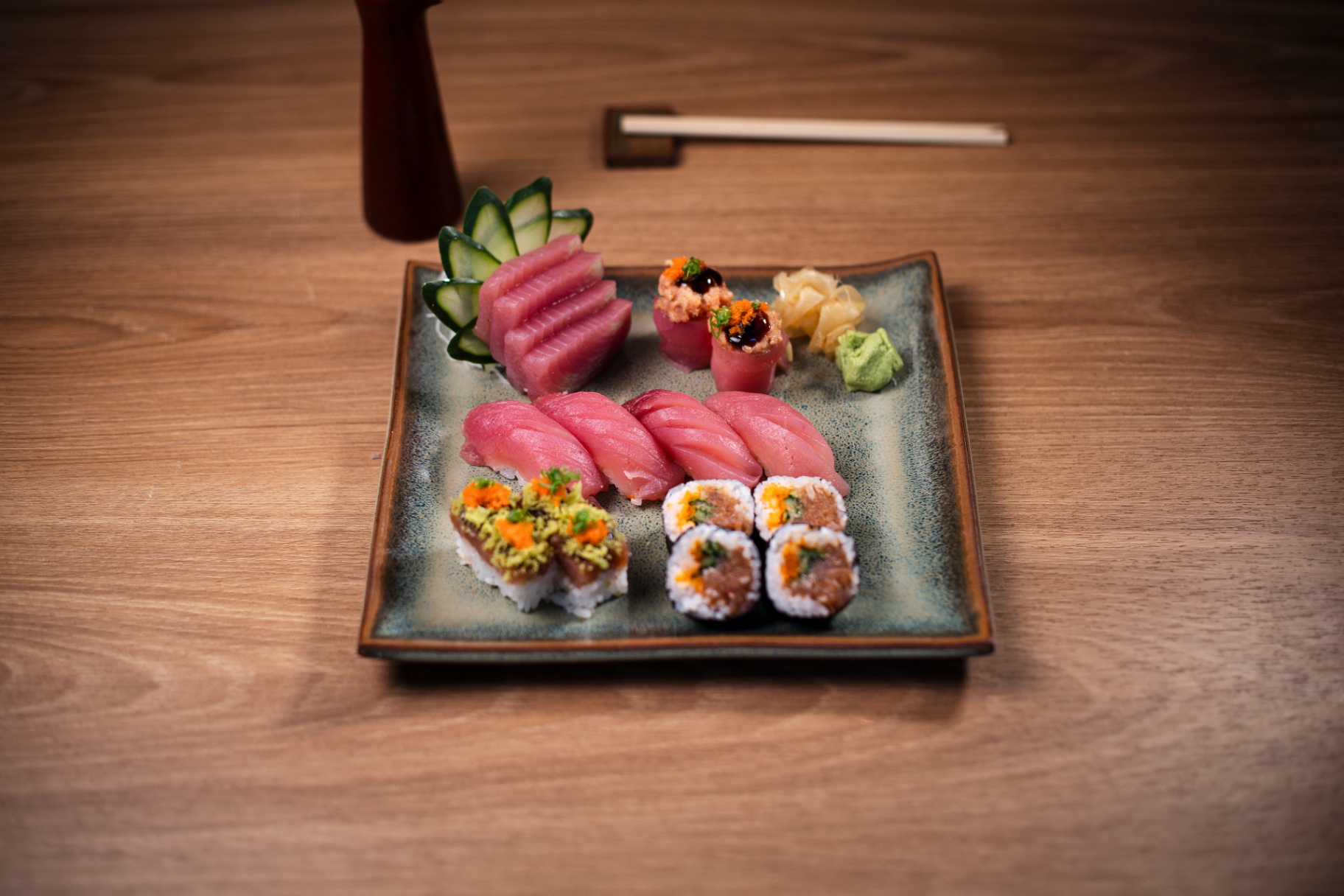 Combinado executivo com sashimi de atum, niguiris e hossomakis em prato quadrado cerâmico sobre madeira