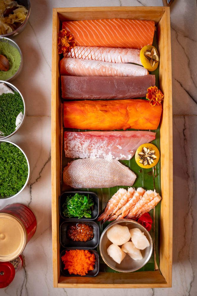 Bandeja de madeira vista de cima com cortes de salmão, atum, peixe branco, camarão e ovas